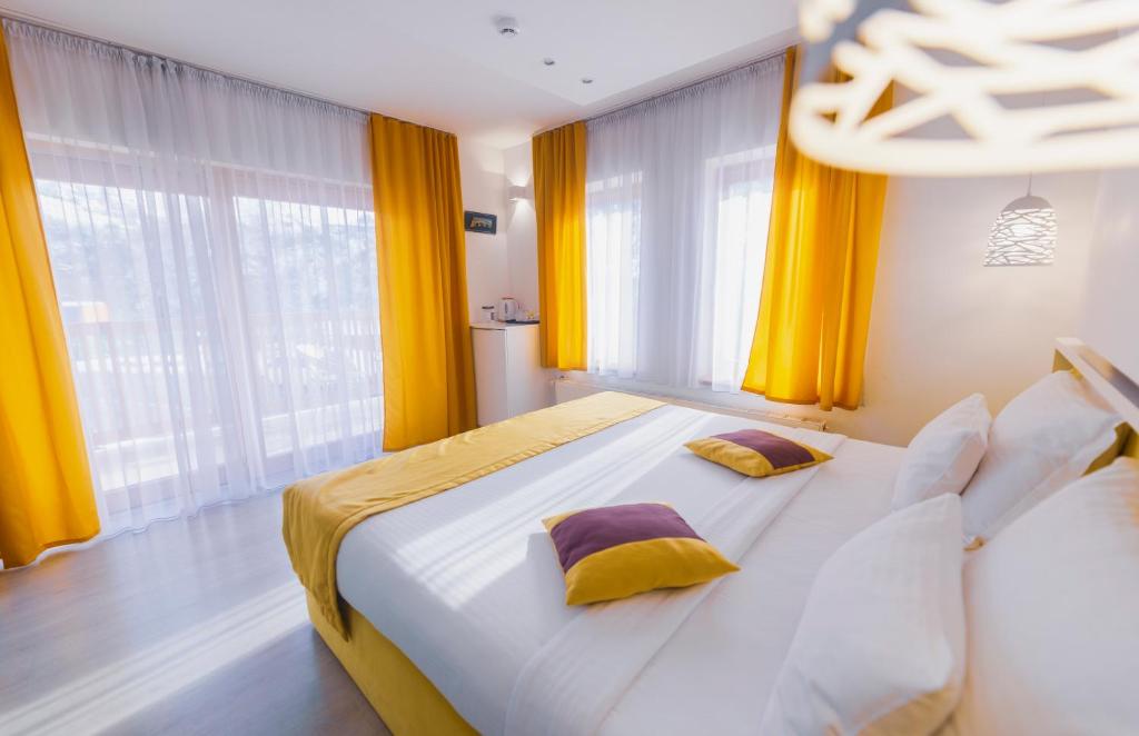 a bedroom with a large bed with yellow curtains at Hotel Boutique Libris in Sarajevo