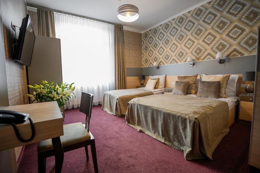 a hotel room with two beds and a flat screen tv at Hotel Kazimierz in Krakow