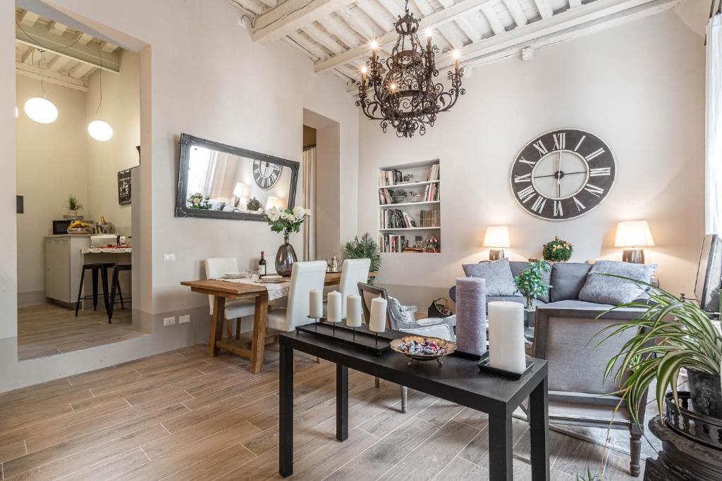 uma sala de estar com uma mesa e um relógio na parede em Casa Janca, Find sanctuary at extraordinary rates! Luxury Smart Apartment in Central Lucca em Lucca