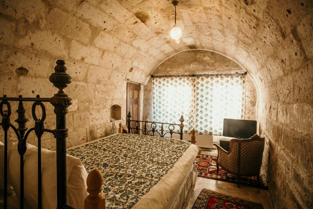 a bedroom with a bed and a tv in a room at Village Cave House Hotel in Göreme