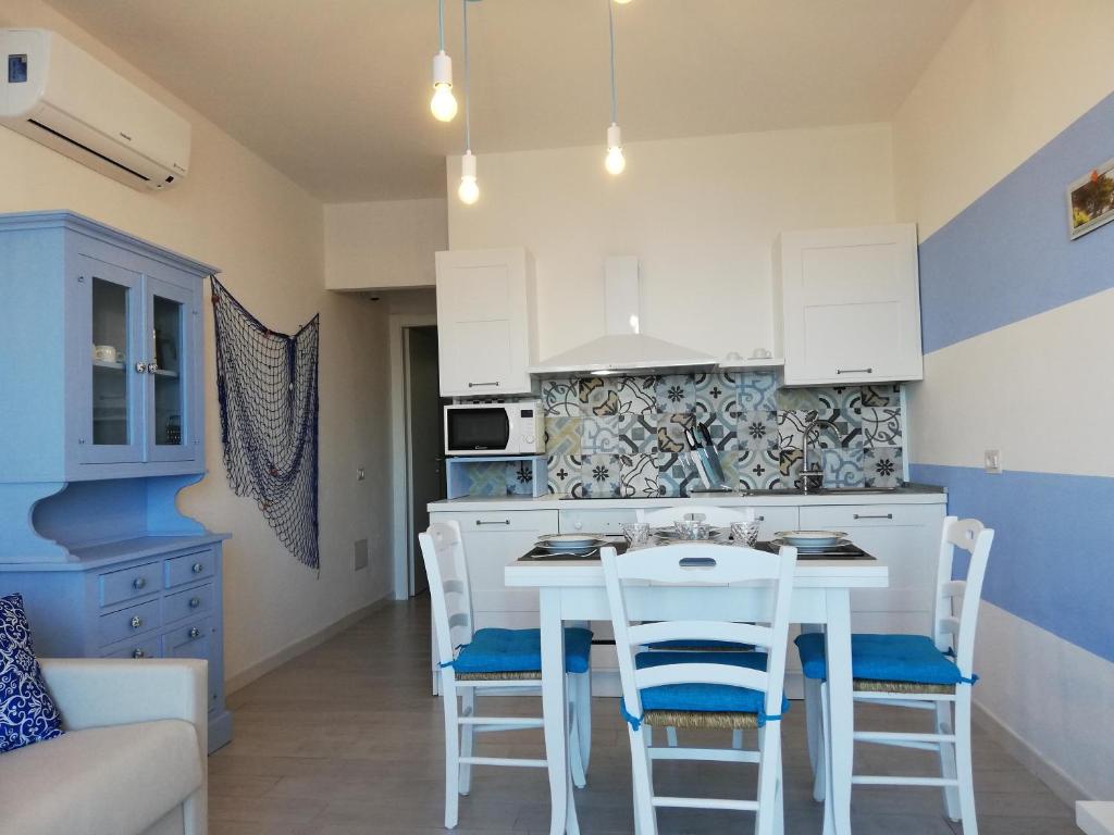a kitchen with white cabinets and a white table and chairs at Suite Smeralda sea view in Castelsardo