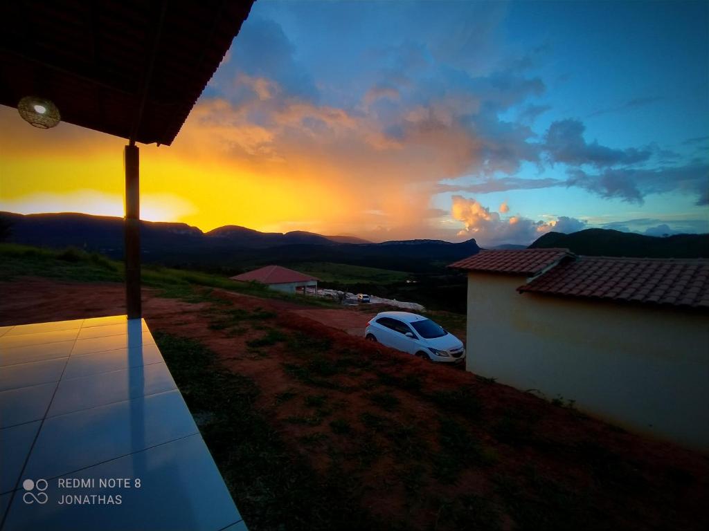 a car parked next to a house with a sunset at Chalé Mirante Das Serras Ibicoara-BA in Ibicoara