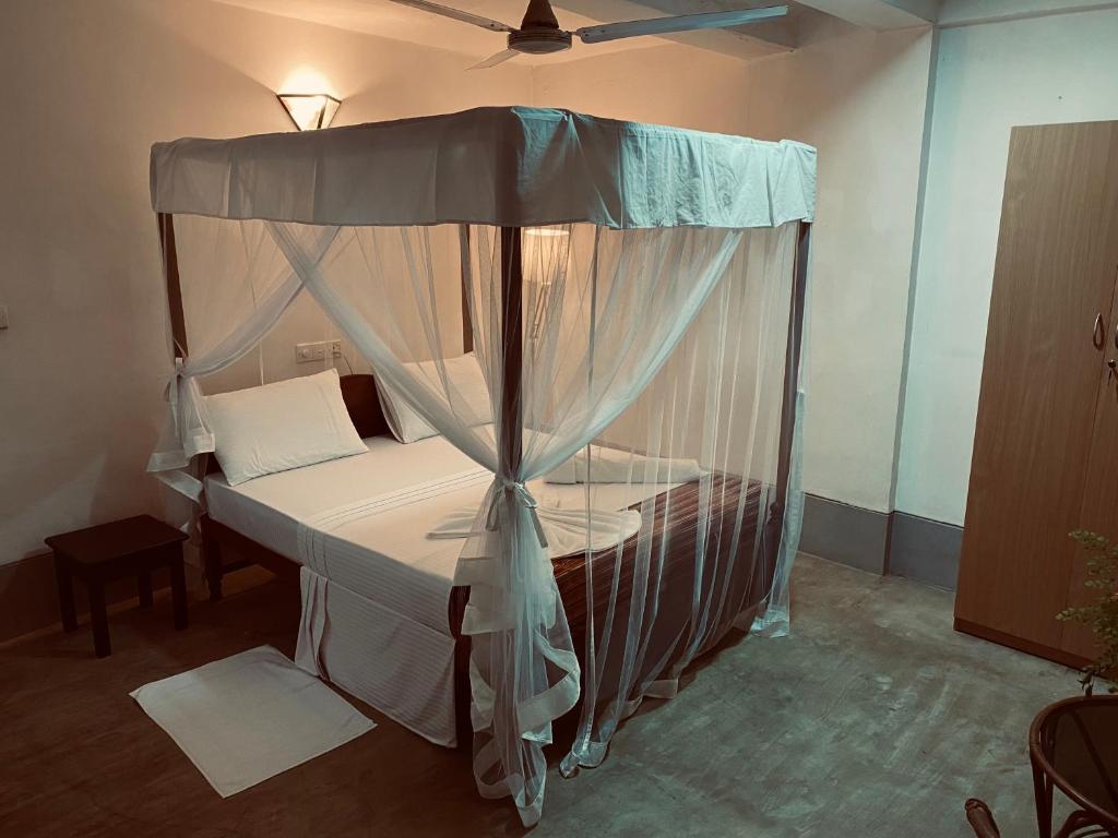 a bedroom with a bed with a canopy at Una Beach Hotel & OLU Cafe in Unawatuna