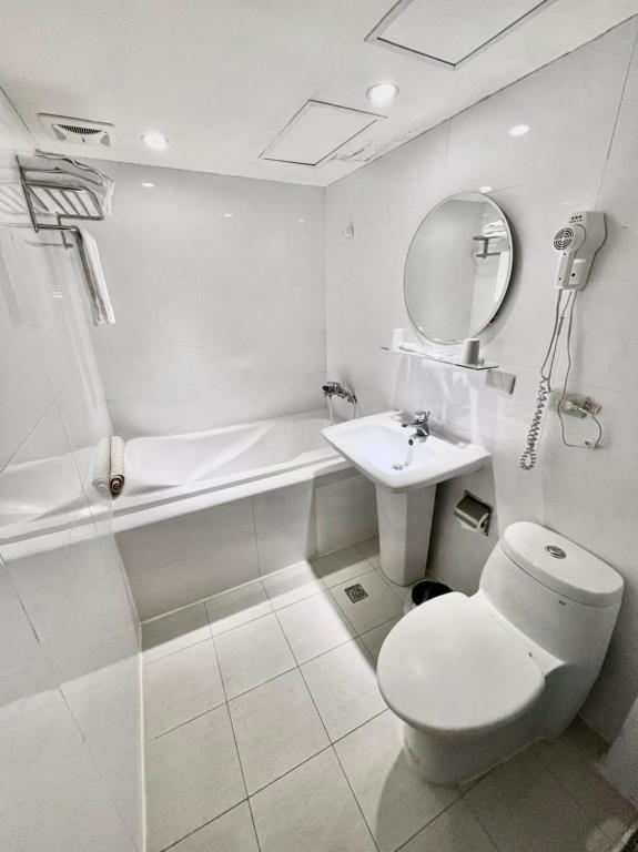 a white bathroom with a toilet and a sink at Meadow Hotel Taipei in Taipei