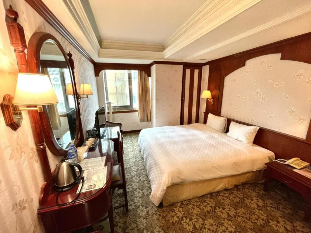 Meadow Hotel Taipei في تايبيه: غرفة في الفندق بها سرير ومكتب به مصباح