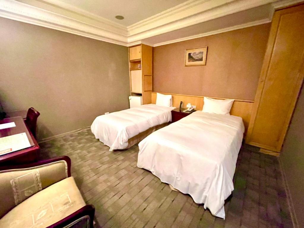 two beds in a hotel room with white sheets at Meadow Hotel Taipei in Taipei