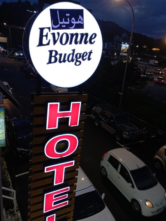 um sinal para um hambúrguer evzone com um carro estacionado num parque de estacionamento em Evonne Budget Hotel em Tanah Rata