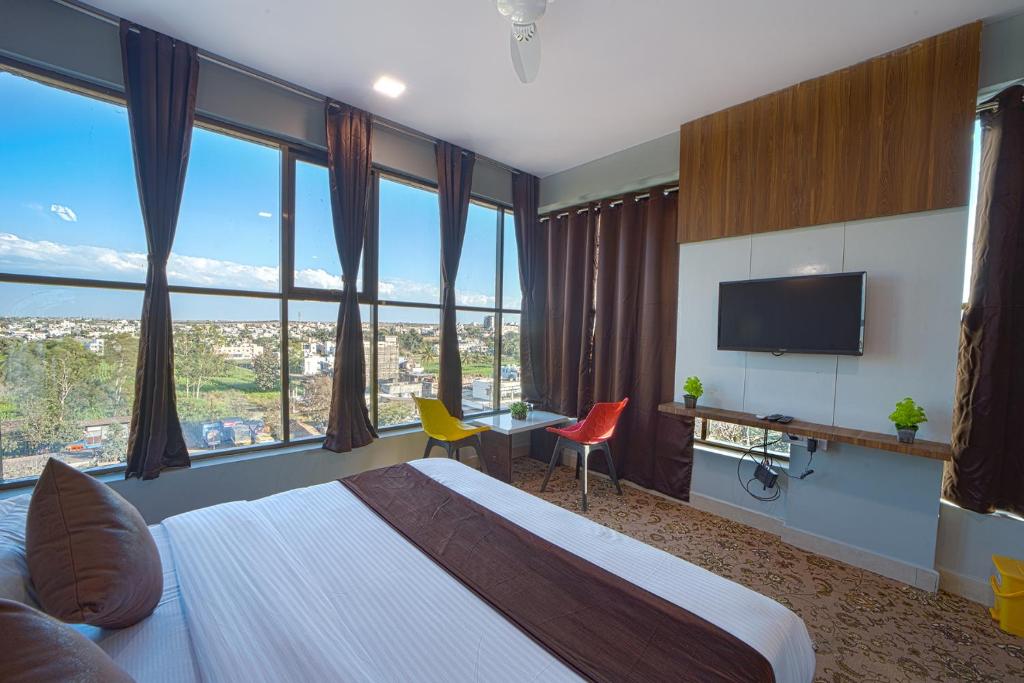 a hotel room with a bed and a desk with a television at Hotel Jurkis, Kolhapur in Kolhapur