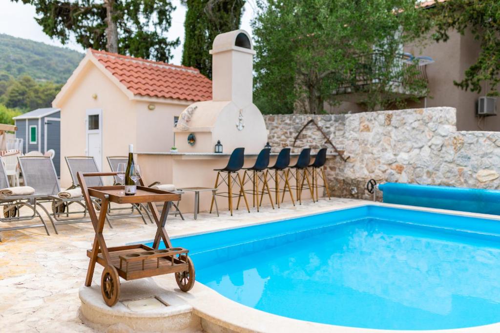 einen Pool mit einem Tisch und Stühlen neben einem Haus in der Unterkunft Villa Stipe in Stari Grad