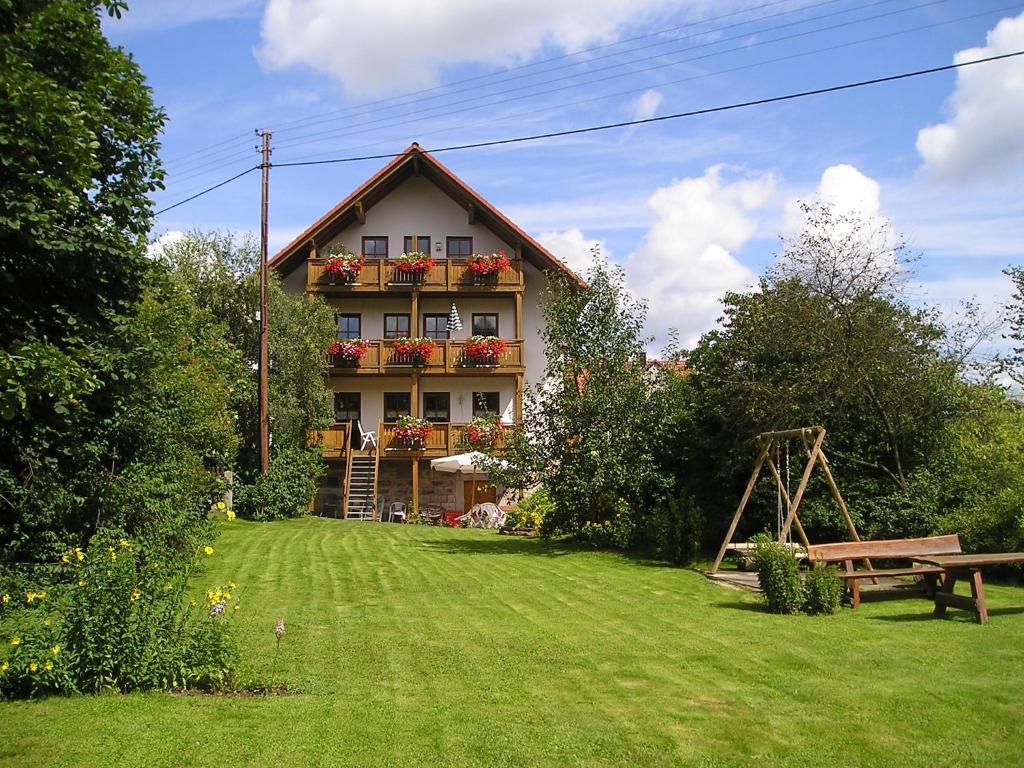 ein Haus mit einem Hof mit einer Bank davor in der Unterkunft Gästehaus & Ferienhof Hüfner in Speicherz