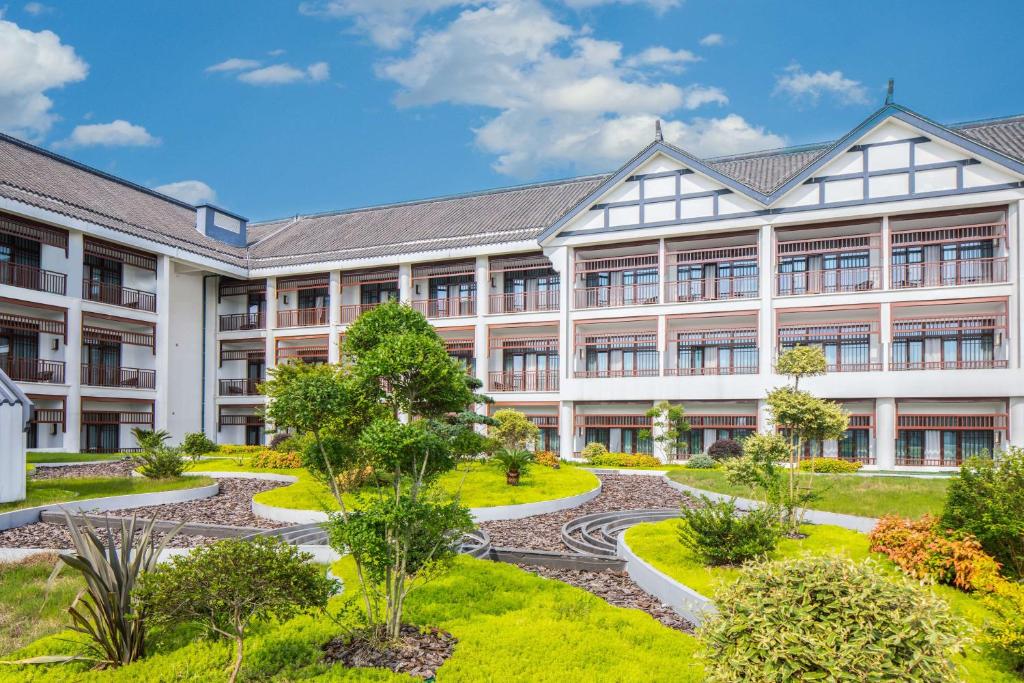 an office building with a garden in front of it at Radisson Blu Resort Wetland Park in Wuxi