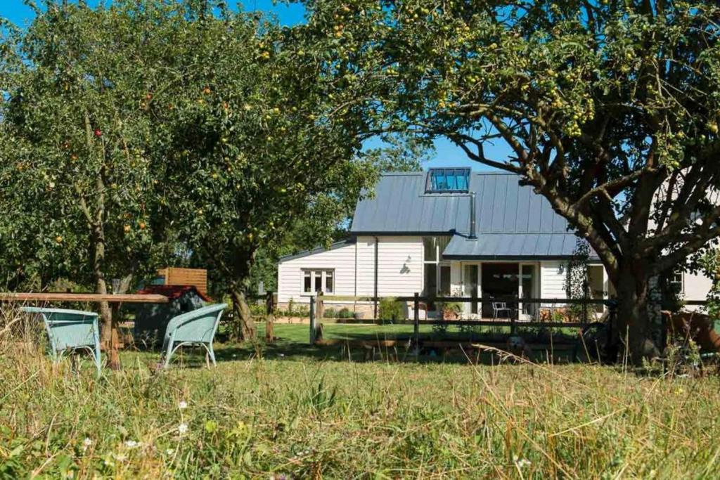 a white house with two chairs and a tree at Skylarks, enjoy the decking overlooking your garden and wildflower meadow in Old Newton