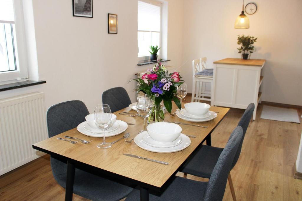 una mesa de madera con sillas, platos y flores. en Ferienhaus Traumblick direkt am See, en Weissenstadt