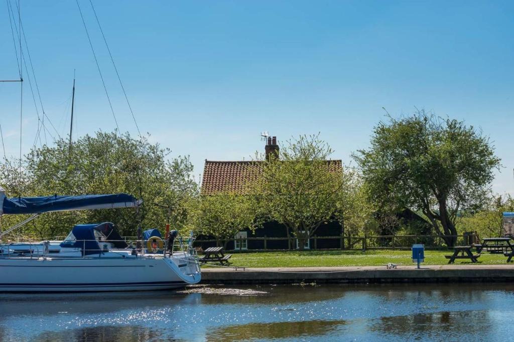 un barco está atracado en el agua junto a un parque en Navigation Cottage on the Historic Sea Lock overlooking the Nature Reserve, en Maldon