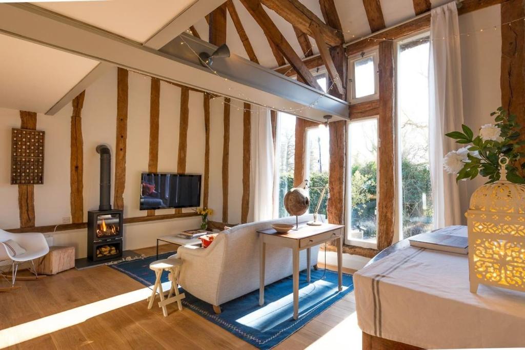 a living room with a bed and a fireplace at Deepwell Granary is a lovely thatched barn with attached meadow woodland in Buxhall