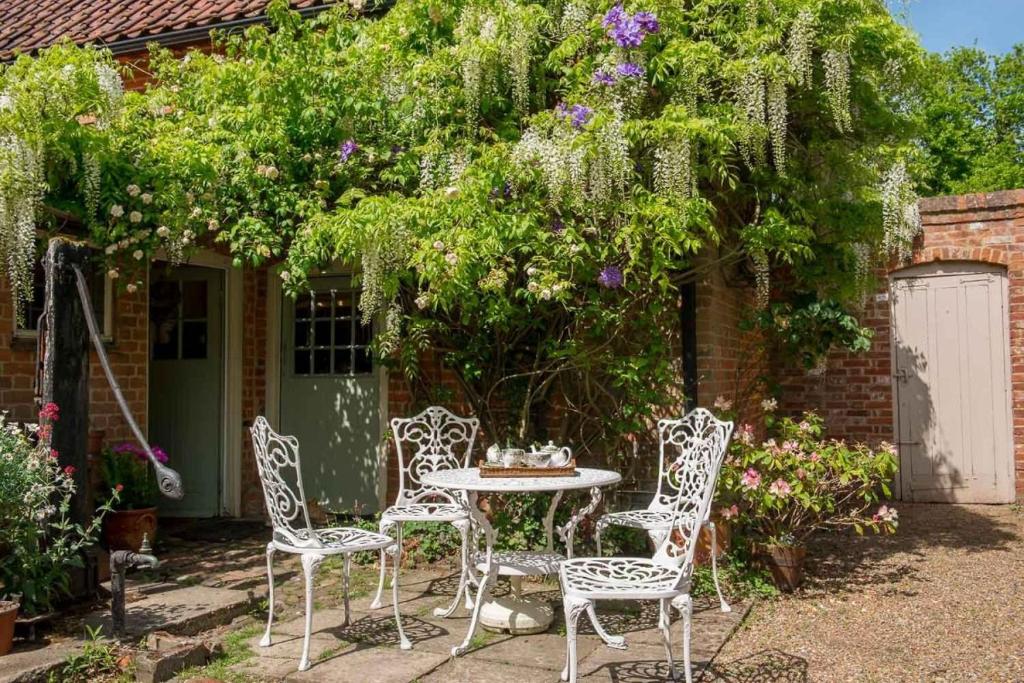 a patio with a table and chairs in a garden at Cissys Cottage in a Nature Reserve, 7 minutes from Aldeburgh seafront 