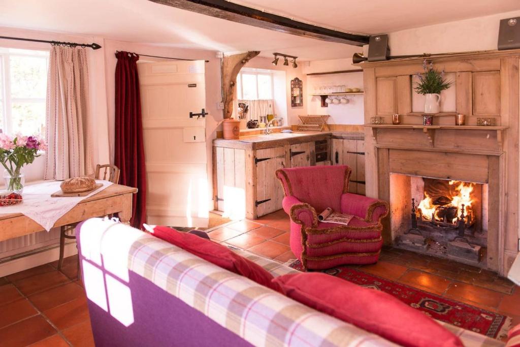 ein Wohnzimmer mit einem Sofa und einem Kamin in der Unterkunft Farm Cottage a cute C17th cottage a walk across the fields to a great pub 