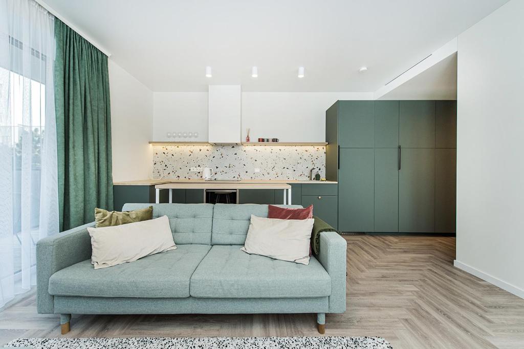 uma sala de estar com um sofá azul e uma cozinha em Cozy Piliamiesčio apartament by URBAN RENT em Kaunas