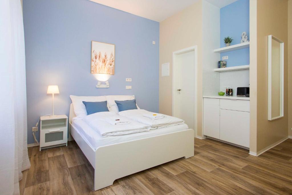 1 dormitorio con cama blanca y pared azul en NEU: Zentral gelegene, stilvoll eingerichtete Zimmer mit eigener Teeküche, en Núremberg