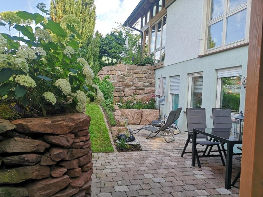un patio con mesa, sillas y pared de piedra. en Ferienwohnung Schmuckkästchen, en Calw