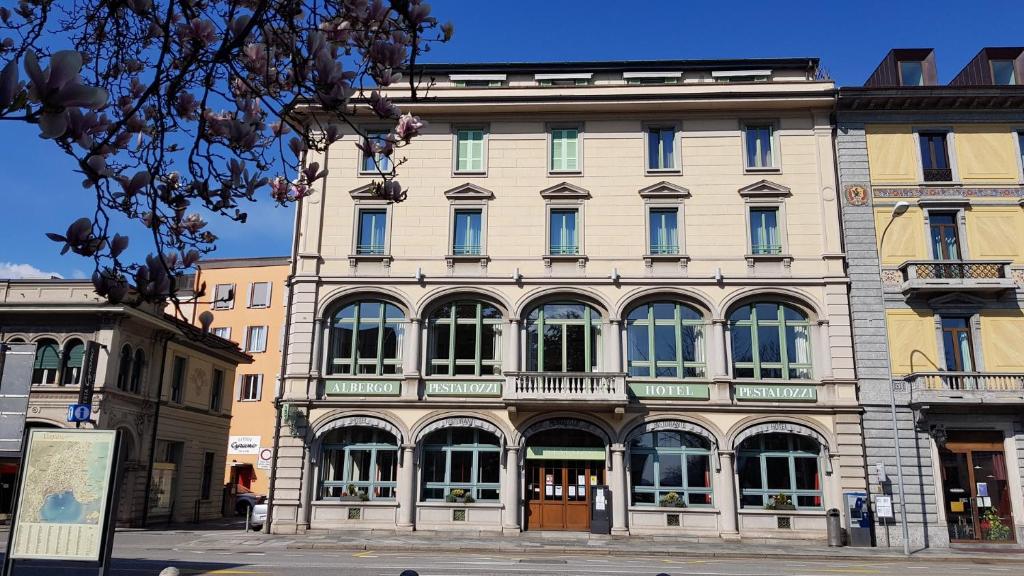 a large building with many windows on a street at Hotel Pestalozzi Lugano in Lugano