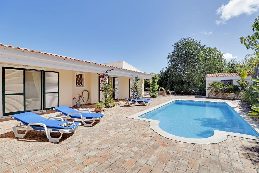 un patio trasero con piscina, sillas y una casa en Algarve Country Villa With Pool by Homing, en Santa Bárbara de Nexe