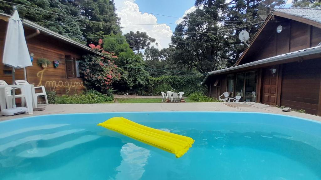 una piscina con un galleggiante giallo davanti a una casa di Chalé Martinho a Gramado