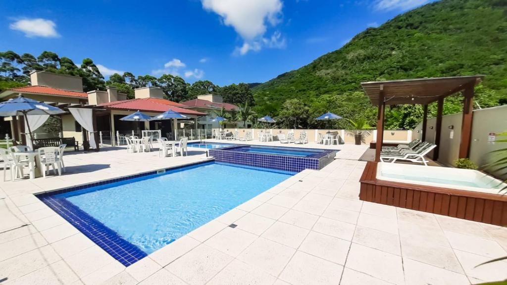 uma piscina num resort com uma montanha ao fundo em Pousada Recanto dos Feijós em Florianópolis
