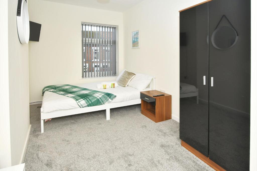 een kleine slaapkamer met een bed en een raam bij Townhouse @ Hall O Shaw Street Crewe in Crewe