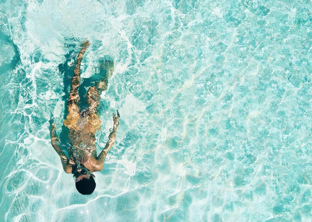 uma pessoa deitada em cima de uma piscina de água em Hotel Argento em St. Julian's