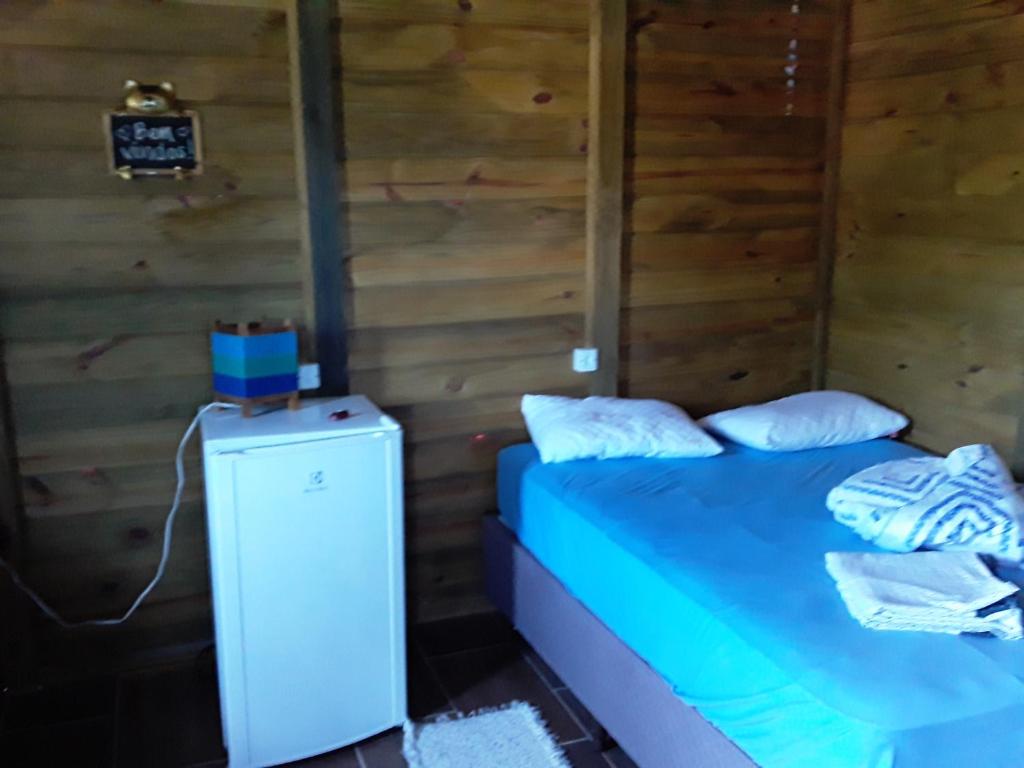 a bedroom with a blue bed and a refrigerator at Cabanas do Lorde in Praia do Rosa