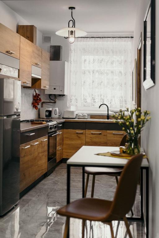 a kitchen with wooden cabinets and a table with chairs at Apartament Miodownik in Międzylesie