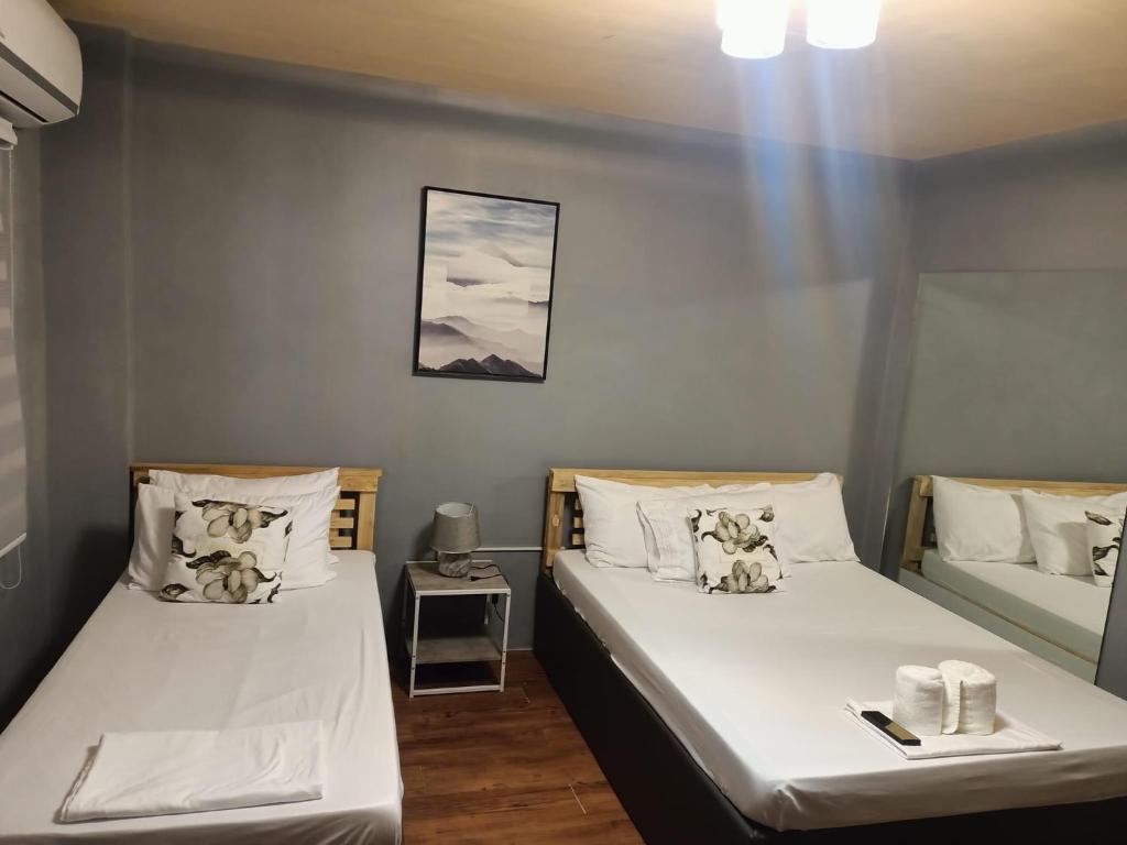 2 camas en una habitación pequeña con sábanas blancas en Djci Apartelle with kitchen n bath 211-209 en Cabanatuan