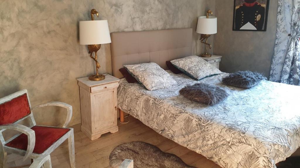 a bedroom with a bed and a lamp and a chair at la maison porte bonheur in Chantelle