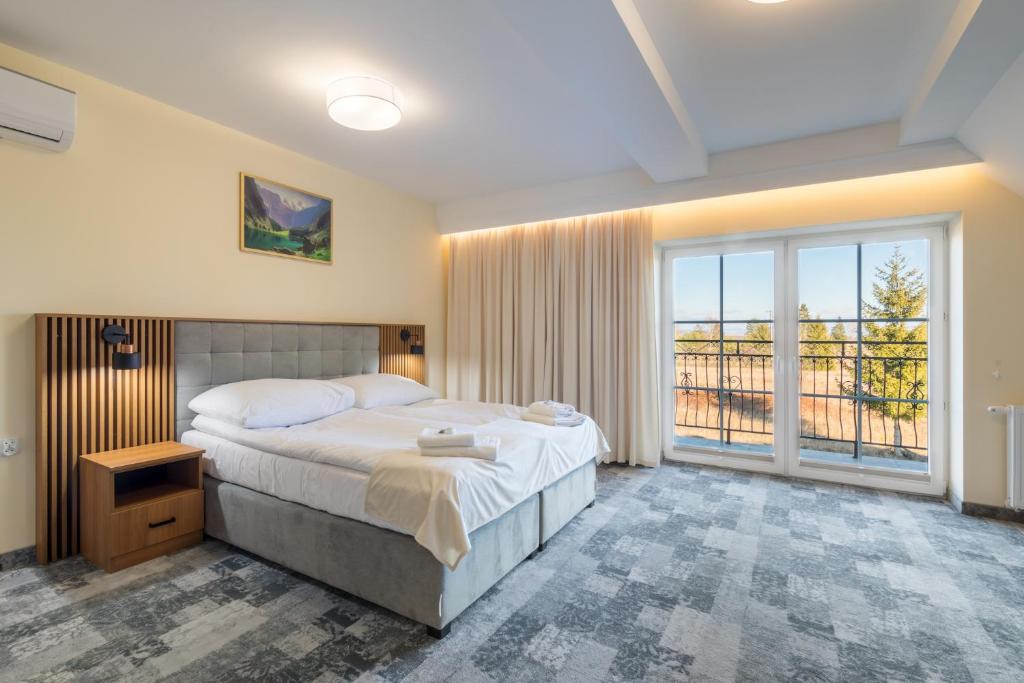 a bedroom with a large bed and a large window at Hotel Perła Dunajca in Czarny Dunajec