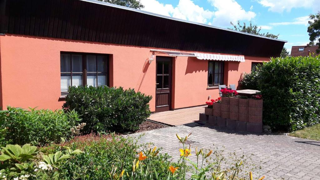 a red house with a wooden porch and a yard at Ruegen Fewo 108 1 in Zudar