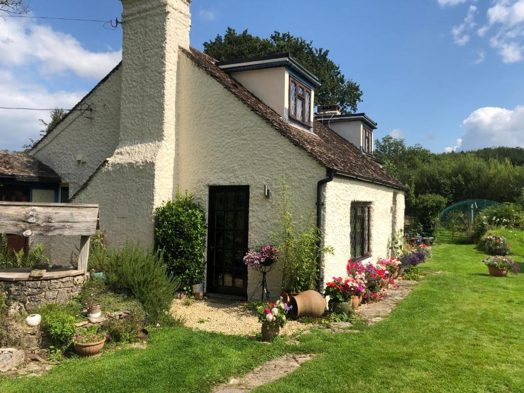 a small white house with flowers in the yard at Chaseborough farm in Wimborne Minster