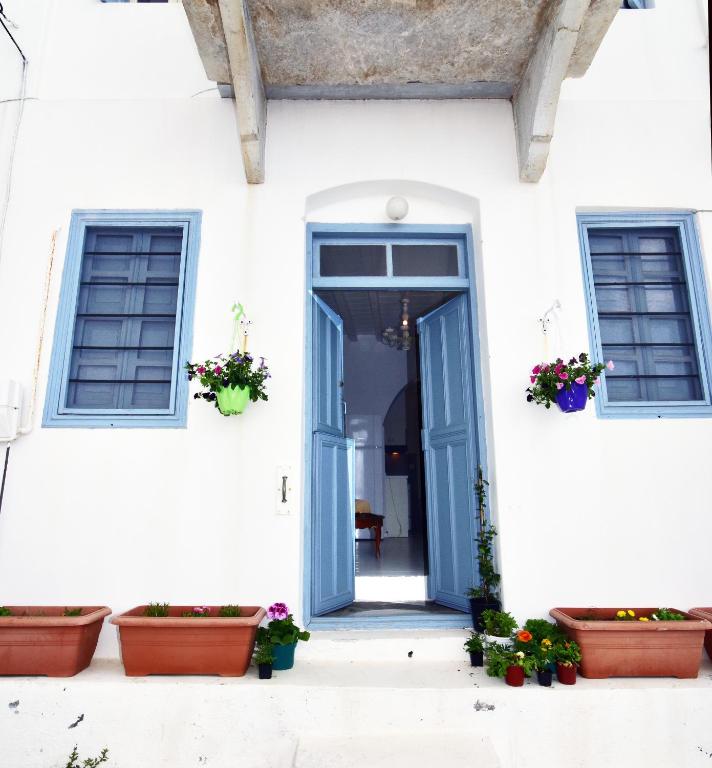 a white house with a blue door and potted plants at Thomas Traditional House in Chora in Amorgos