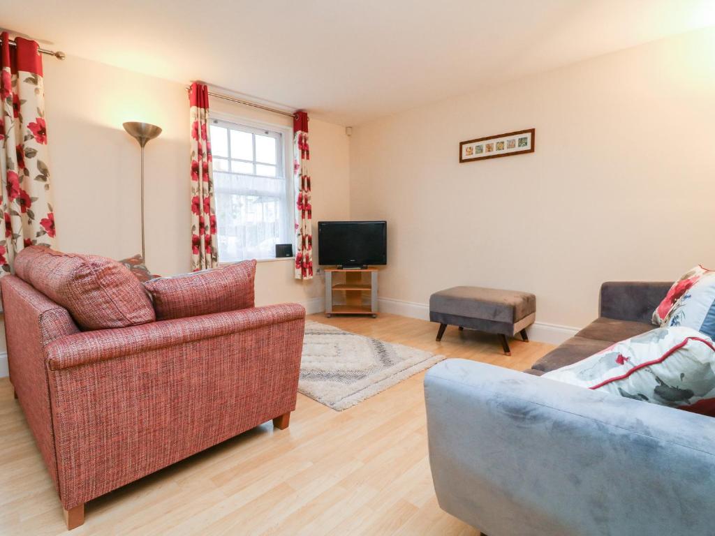 a living room with two couches and a tv at 1 Tregonwell Court in Minehead