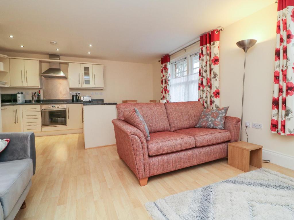 a living room with a couch and a kitchen at 1 Tregonwell Court in Minehead