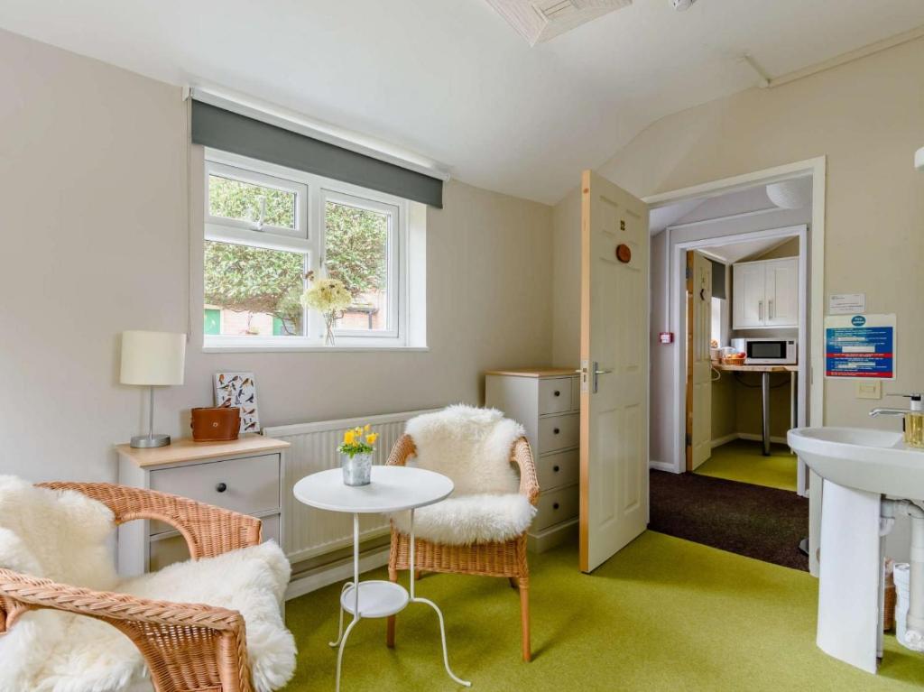 Cette petite chambre comprend une table, des chaises et un lavabo. dans l'établissement Claridge House, à Lingfield