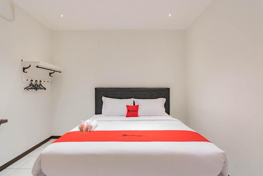 ボゴールにあるRedDoorz Plus @ Pakuan Residence Tajurのベッドルーム(赤い枕と白い大型ベッド付)
