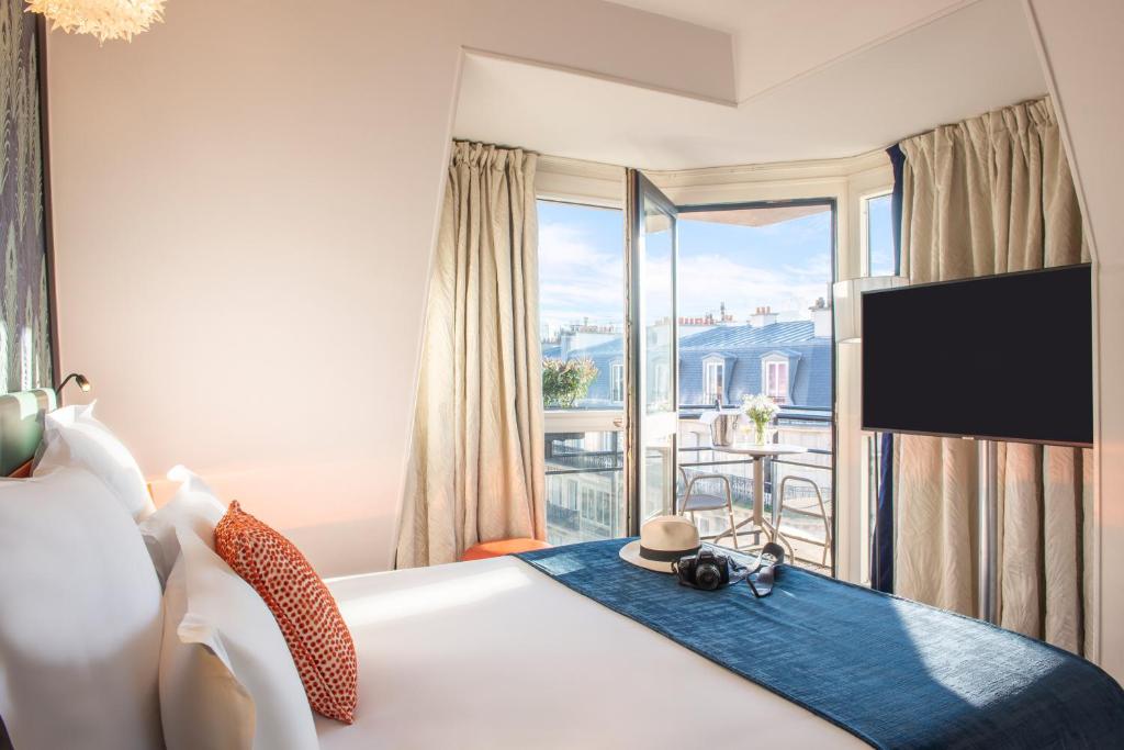 a bedroom with a bed with a view of a balcony at Hotel Yllen Eiffel in Paris