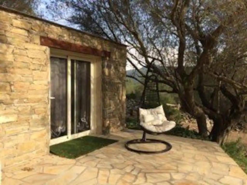 una silla sentada en un patio junto a una ventana en Petite maison en pierre en Saint-Florent