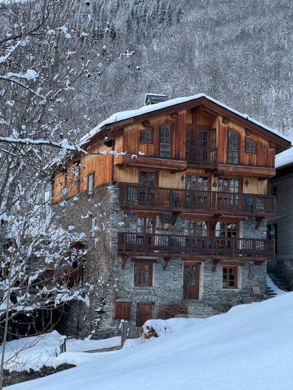 un bâtiment en bois avec un balcon dans la neige dans l'établissement Chalet Altus, à Sainte-Foy-Tarentaise