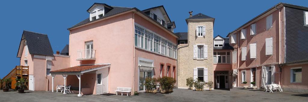 un groupe de bâtiments avec des tables et des chaises dans une cour dans l'établissement Résidence Ana, à Bagnères-de-Bigorre
