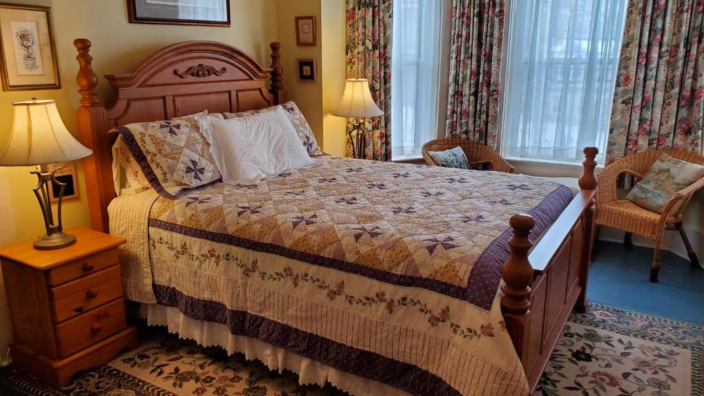 a bedroom with a bed and a lamp and a chair at The Lark & Loon Inn in Annapolis Royal