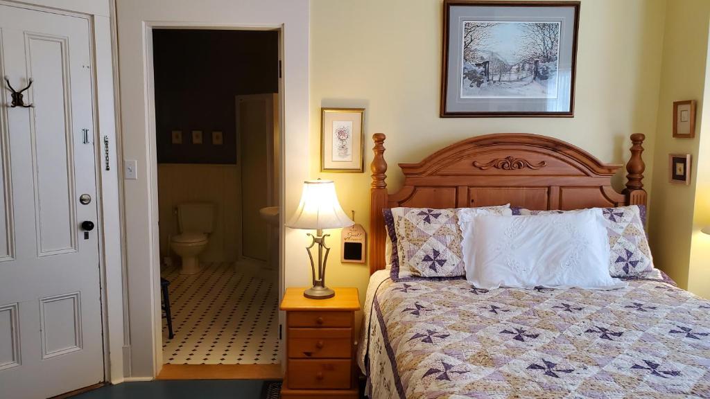 a bedroom with a bed and a lamp on a night stand at The Lark & Loon Inn in Annapolis Royal