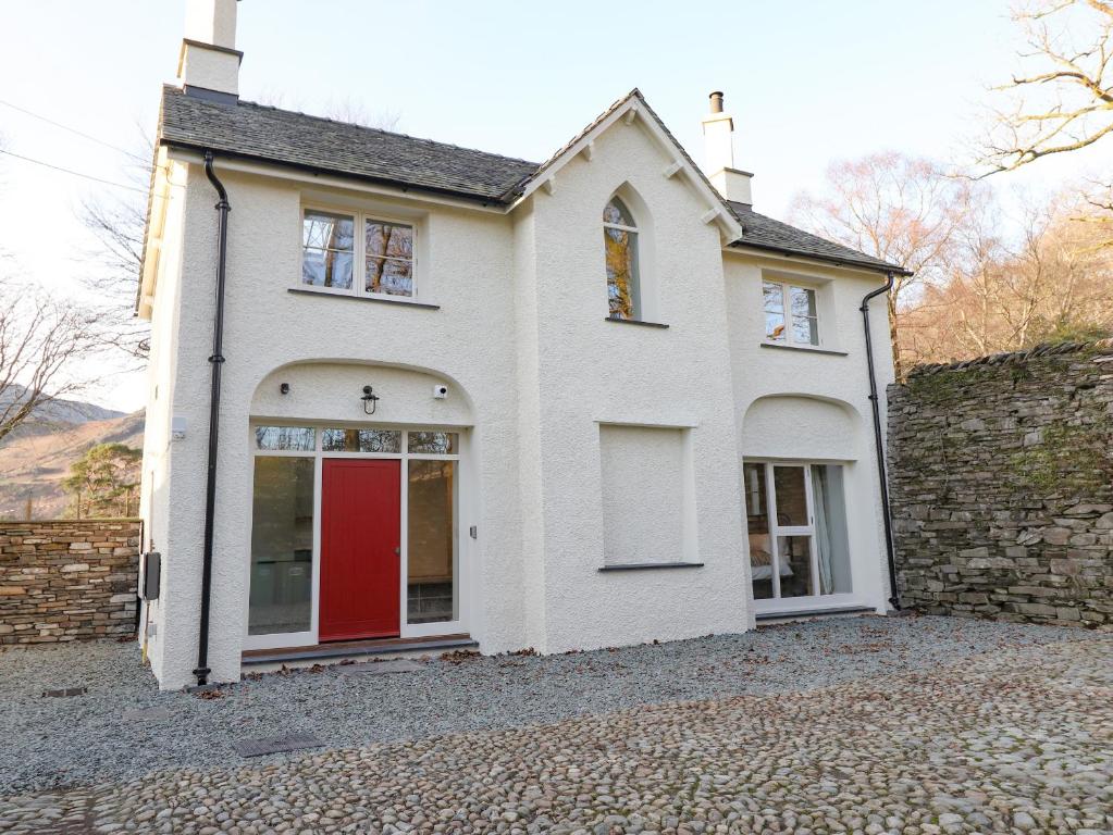 a house with a red door on a stone driveway at Guardswood Cottage in Coniston