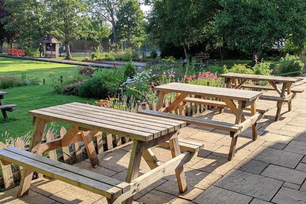 un grupo de mesas de picnic de madera en un parque en Maple House, en Bristol